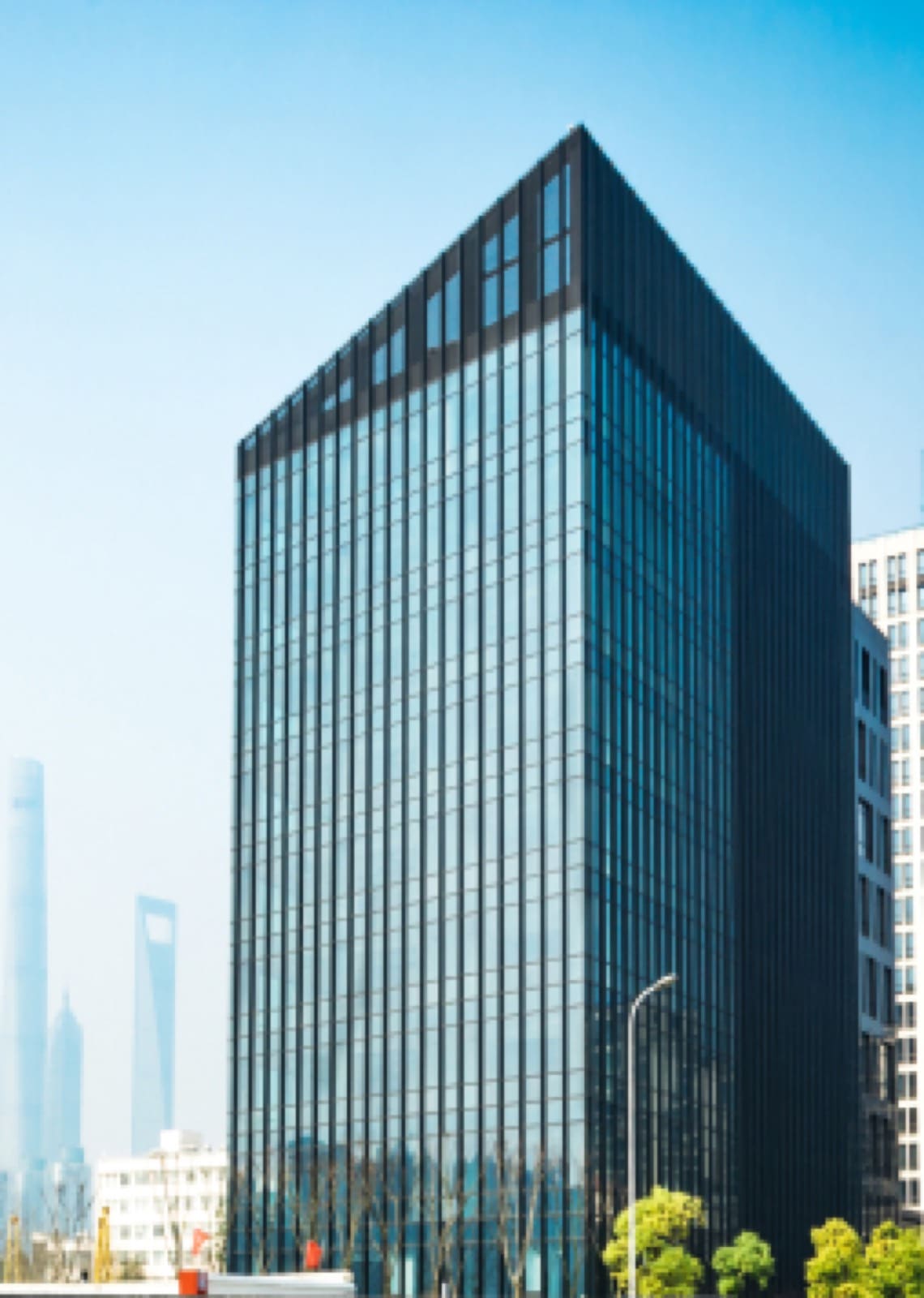 A glass office tower against a blue sky